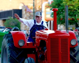 Man on red tractor in parade at Santa Fe Trail Days in Larned, KS